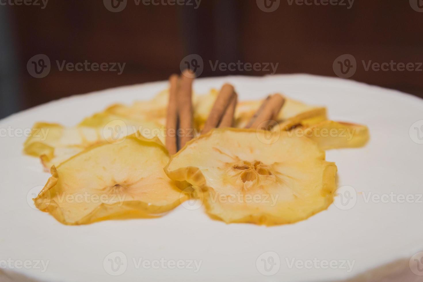 gros plan sur un gâteau à la crème blanc avec des pommes séchées et de la cannelle sur le dessus photo