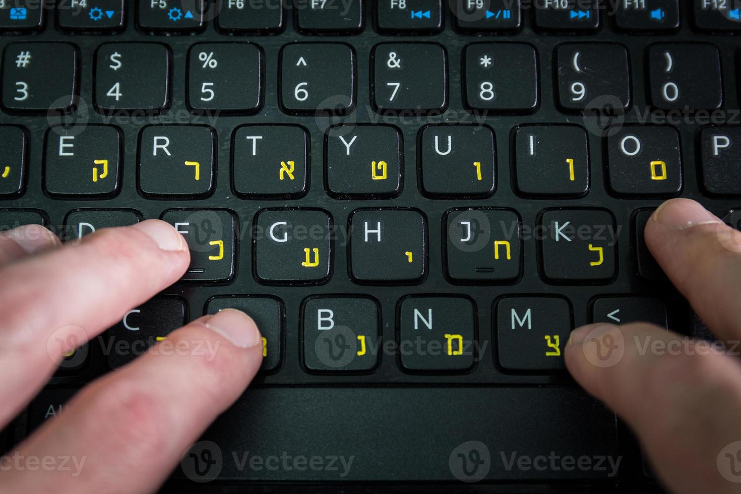 homme tapant sur un clavier avec des lettres en hébreu et en anglais photo