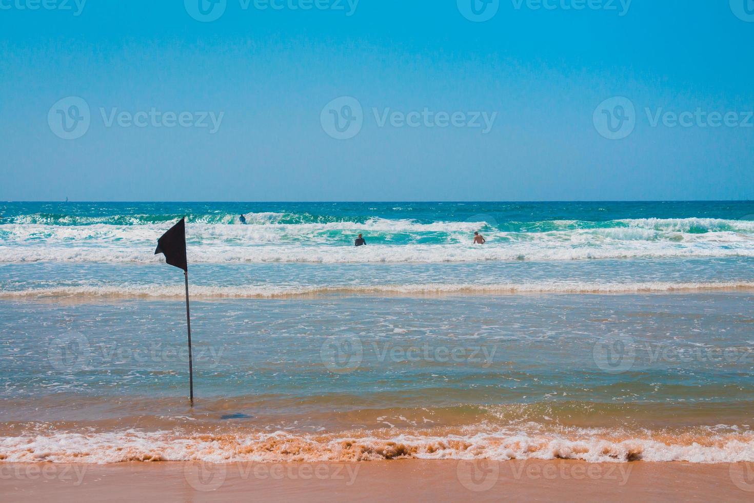 drapeau d'avertissement noir marquant la limite de la zone de baignade sécurisée sur une belle plage avec un ciel bleu et une mer turquoise en israël photo