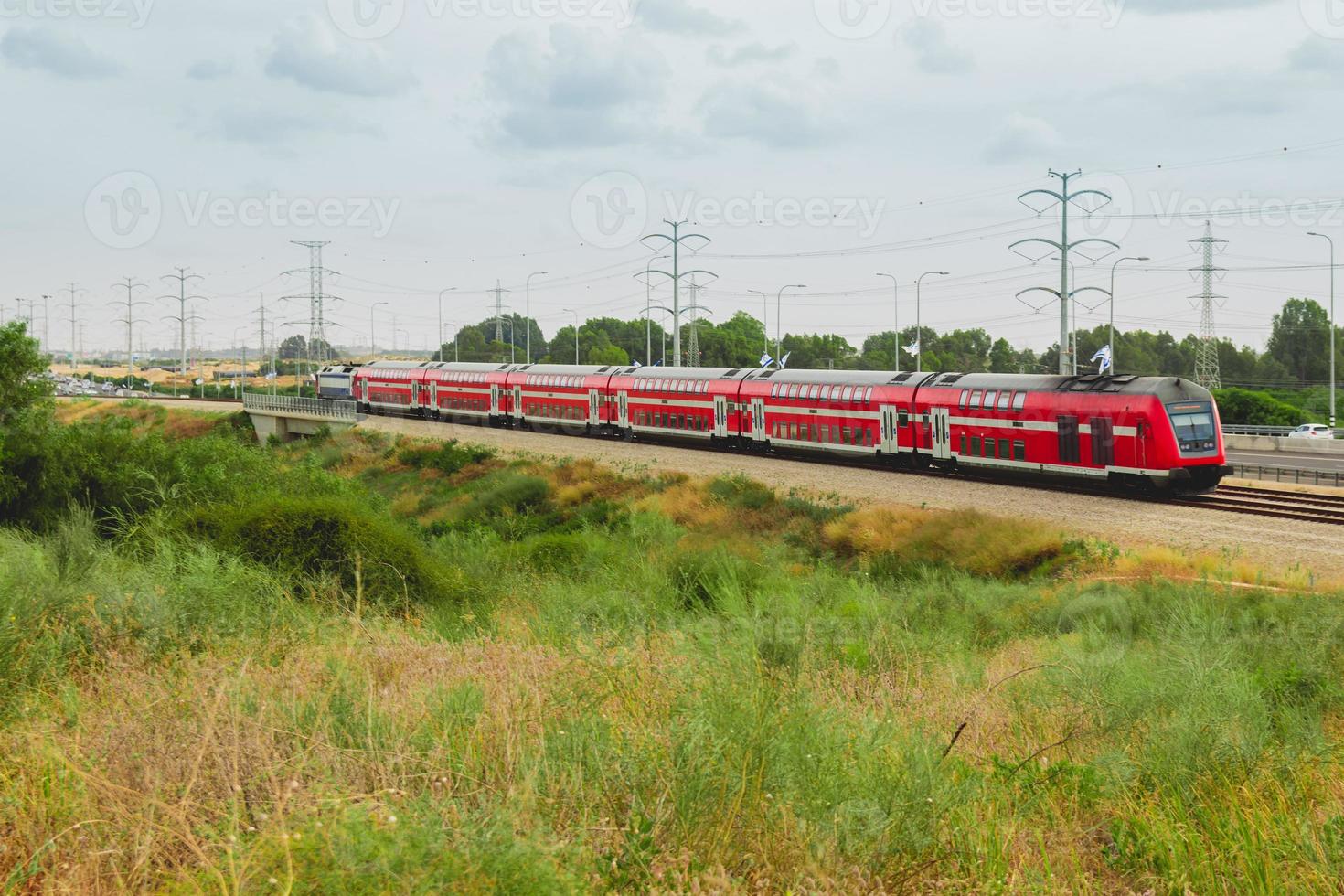 train de voyageurs israélien rouge en mouvement hors de la ville près de l'autoroute 4 photo