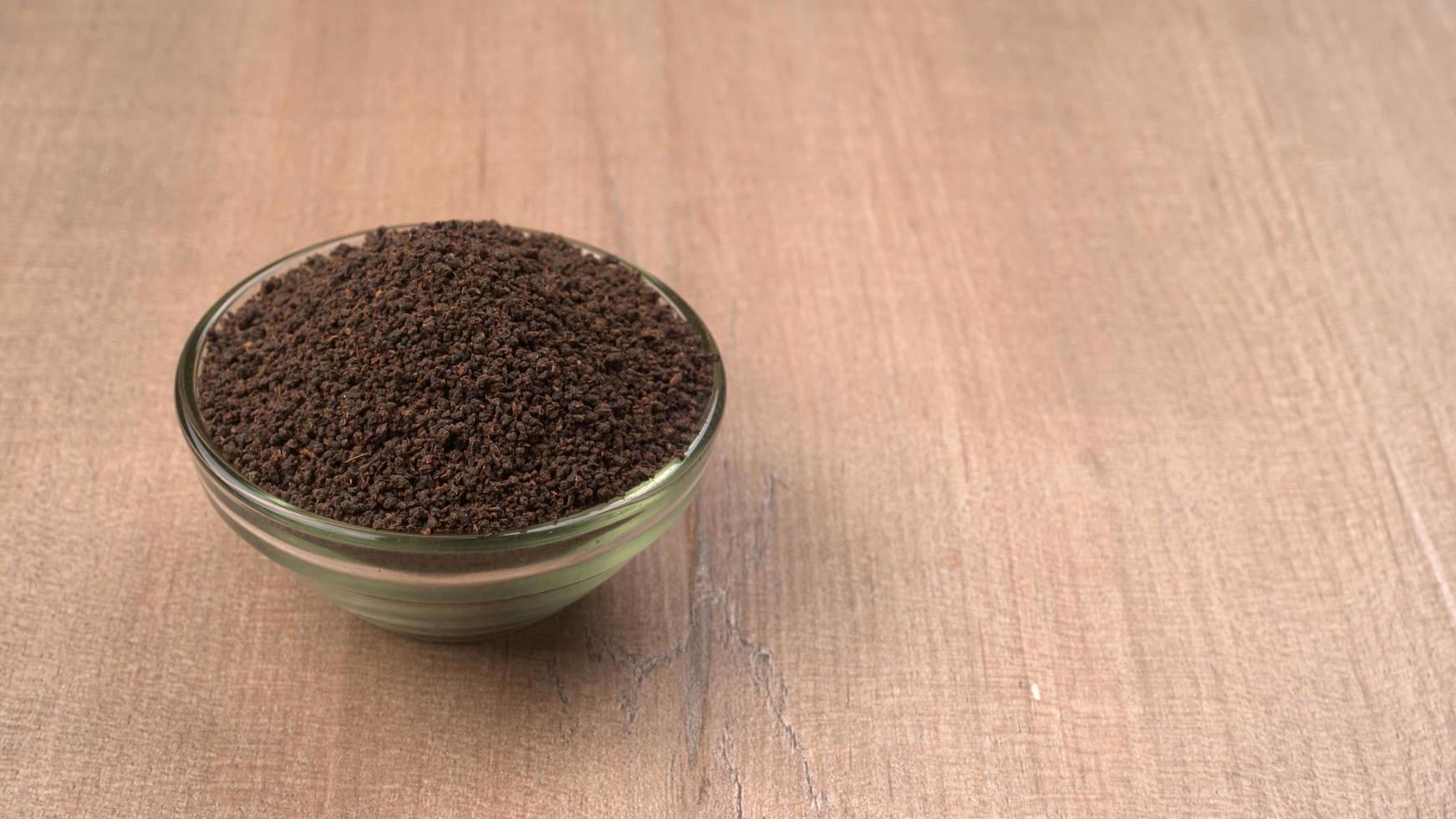 poudre de thé noir ou poudre de thé à poussière sèche, chai patti isolé dans un bol en bois. photo