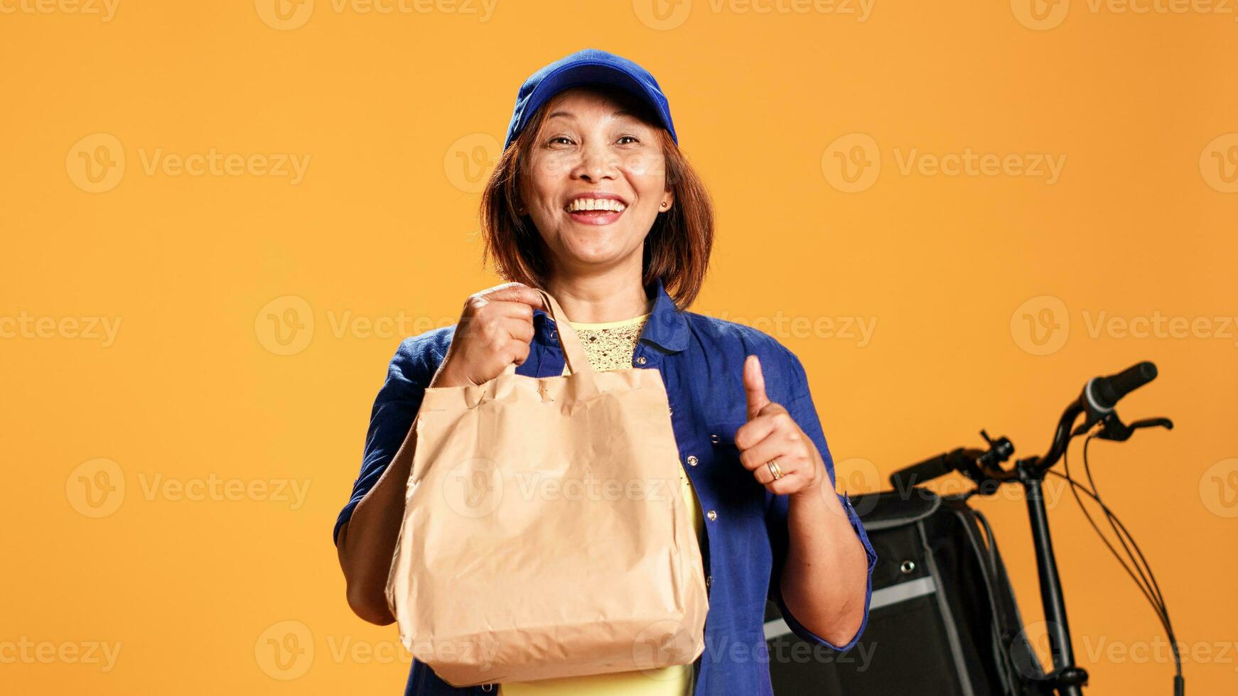 lent mouvement portrait proche en haut coup de impatient asiatique femme attendre pour client à répondre porte, montrant les pouces en haut signe. de bonne humeur nourriture livraison ouvrier remise à emporter repas à client photo