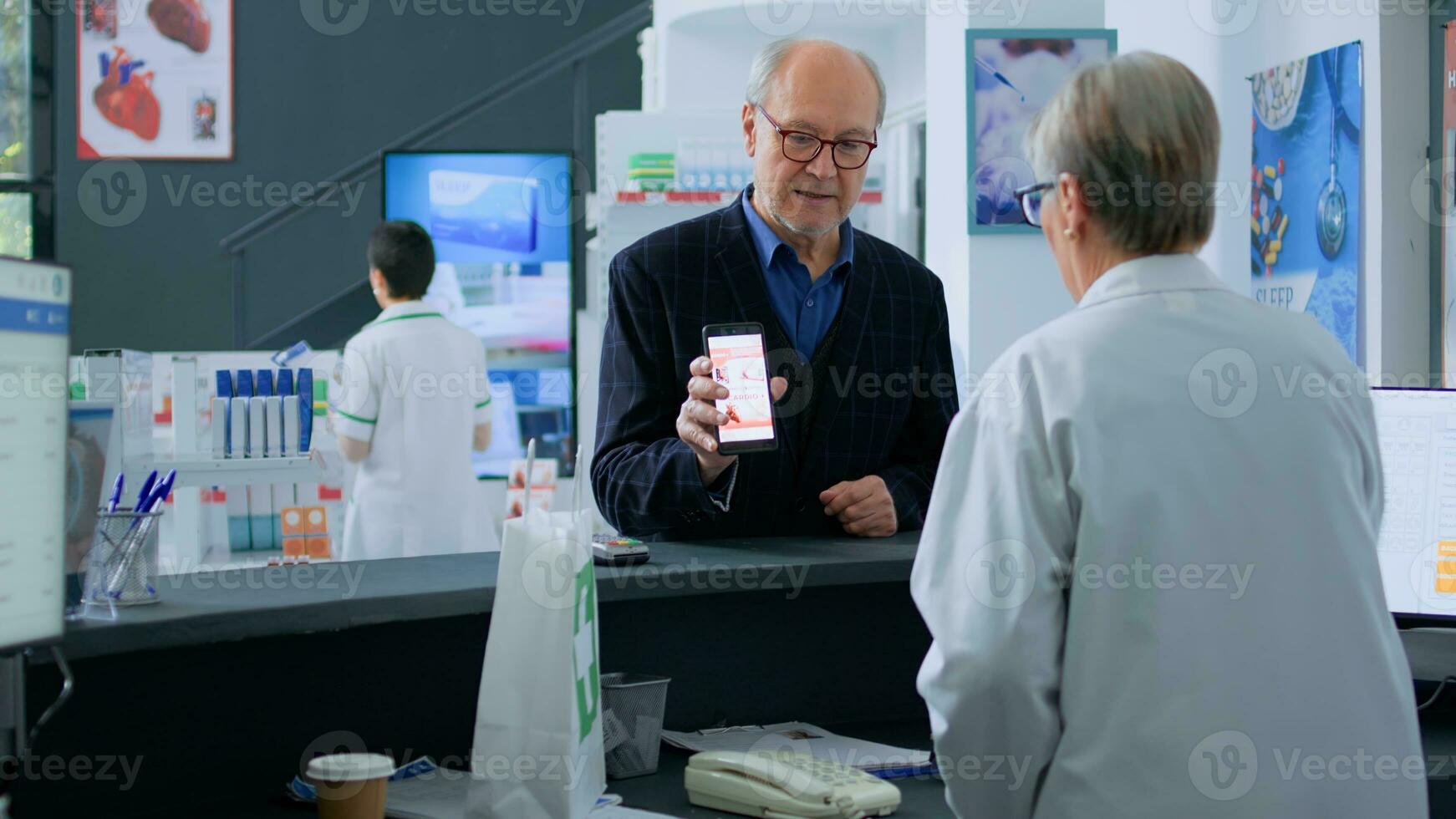 Sénior homme à pharmacie comptoir, montrant pharmacien prescrit cardiovasculaire pilules image sur téléphone intelligent, prêt à acheter il. vieilli soins de santé expert vente client obligatoire des médicaments drogue photo