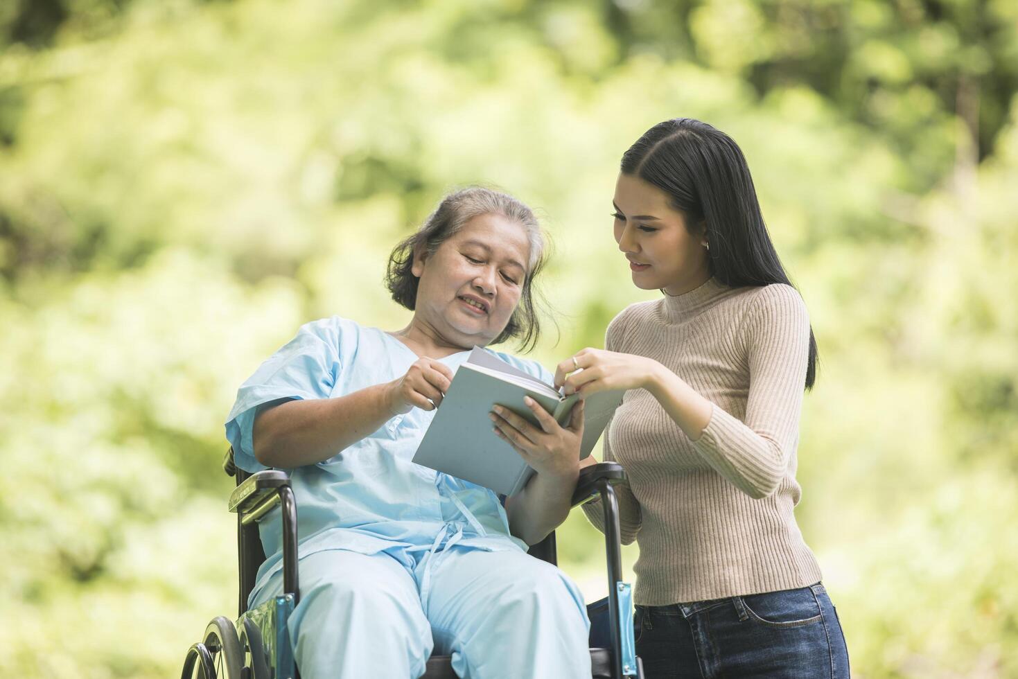 femme heureuse dans un fauteuil roulant lisant un livre avec sa fille au parc photo