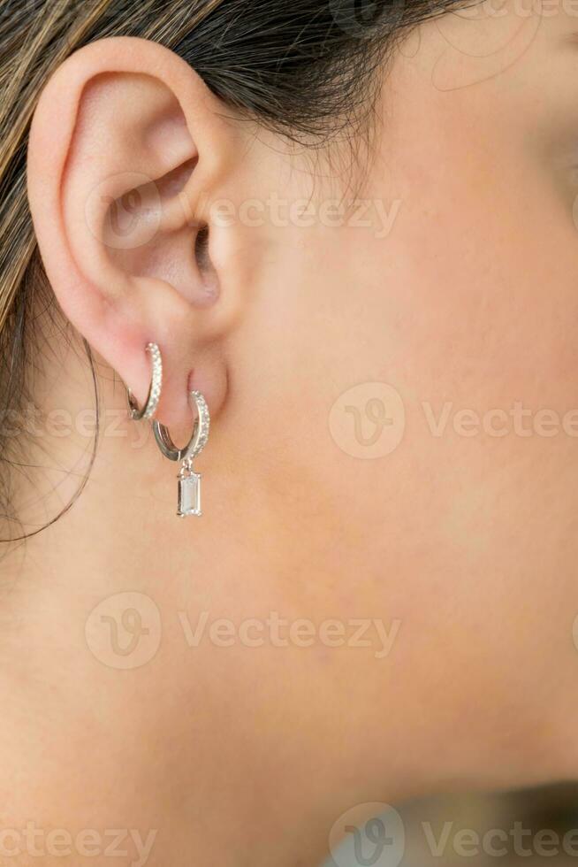 Jeune femme portant argent clair sucré laissez tomber des boucles d'oreilles. photo