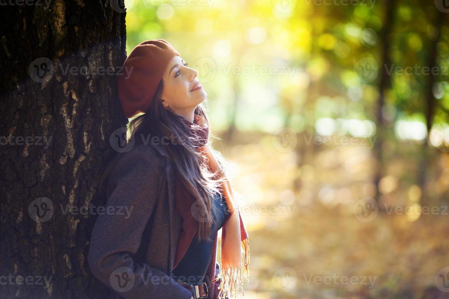 fille dans un béret se tient à côté d'un arbre par une journée ensoleillée d'automne photo