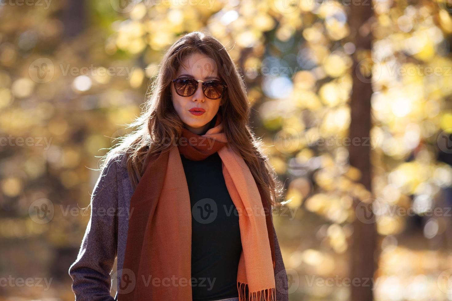 Jeune femme aux cheveux longs et lunettes de soleil dans la forêt d'automne photo