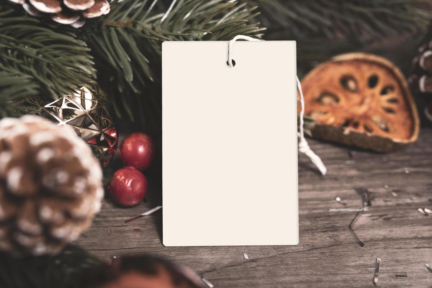 carte de papier d'étiquette de maquette avec décoration de noël de pommes de pin sur fond de table en bois. photo