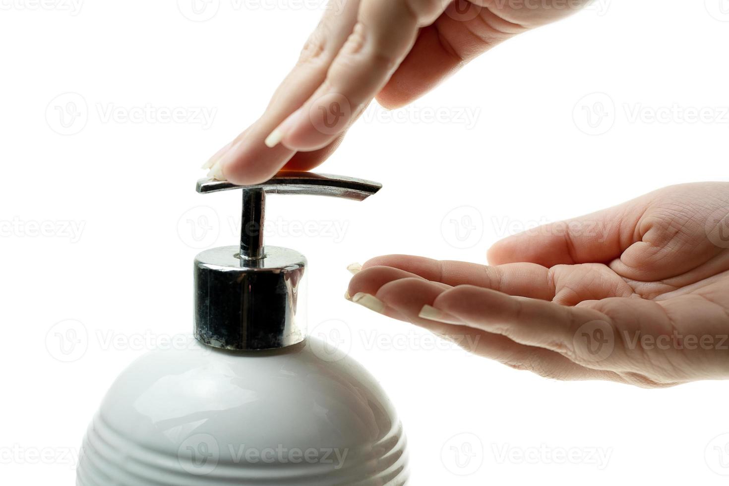 lotion de pompage à la main femme de la bouteille un savon liquide fouet sur fond blanc, dame utilisant du gel d'alcool comme désinfectant pour les mains, belles mains féminines avec crème de gommage transparente photo