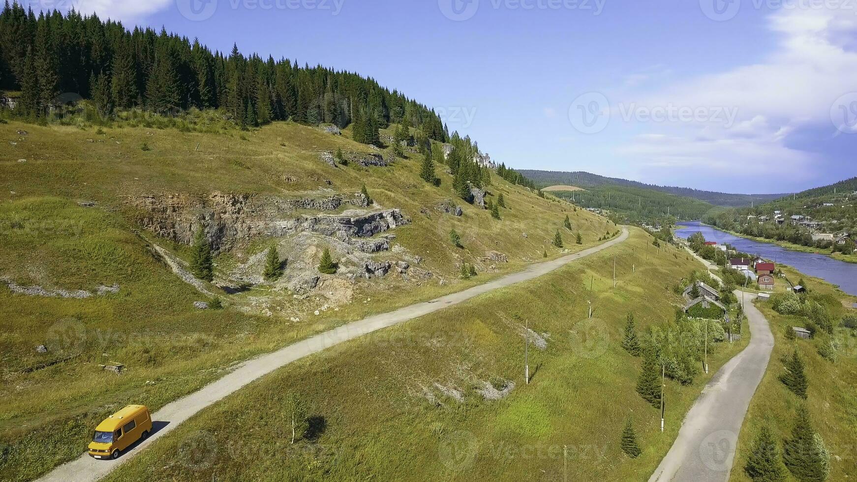 magnifique yeux d'oiseau voir. agrafe. une vert vallonné Montagne sur lequel là sont routes avec voitures et une bus, sur Haut de lequel là est une forêt et une rivière dessous, sur le droite côté vous pouvez voir le autre banque photo