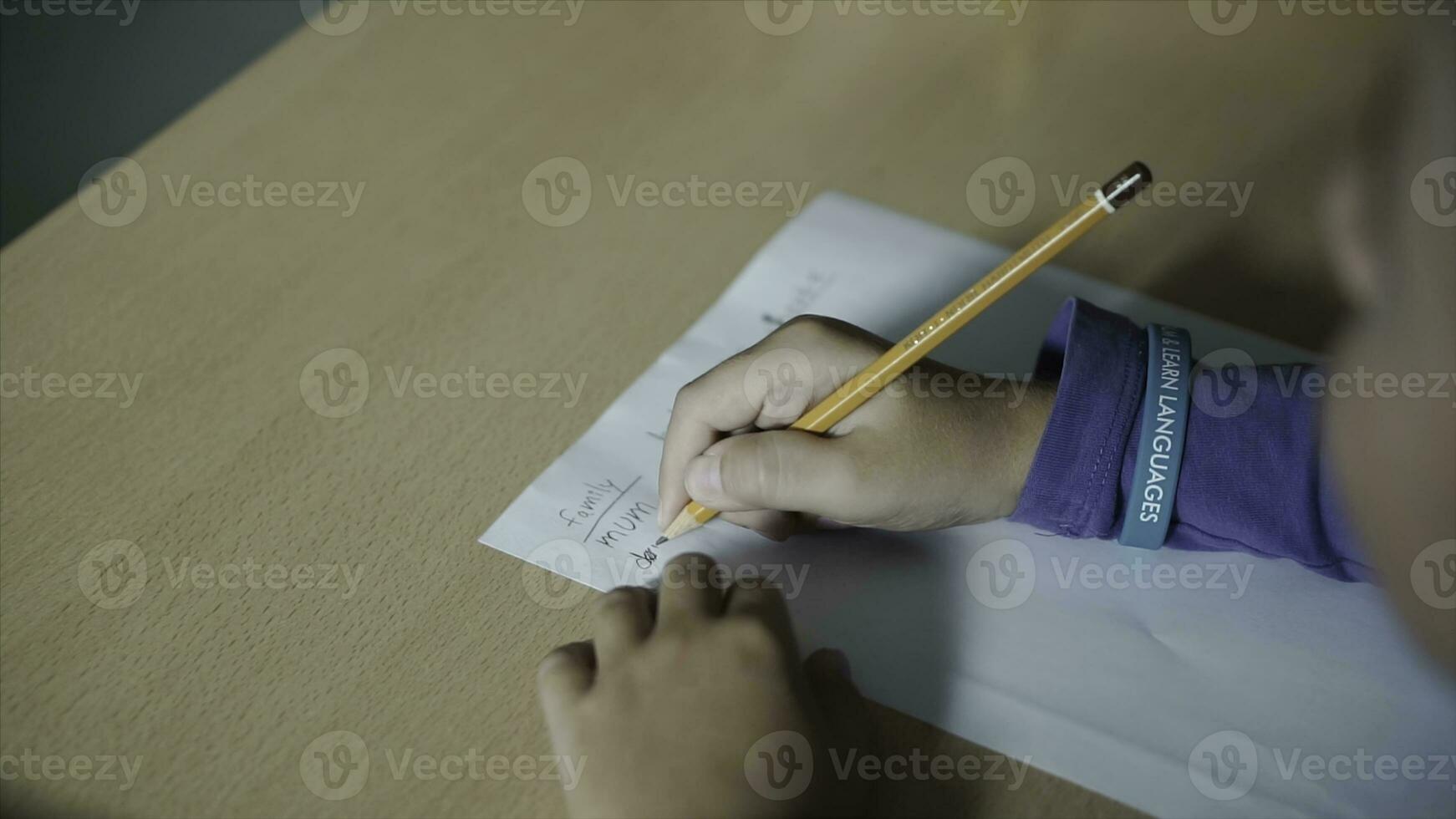 une mignonne peu garçon l'écriture avec une crayon proche en haut. agrafe. peu garçon est l'écriture avec une crayon sur papier photo