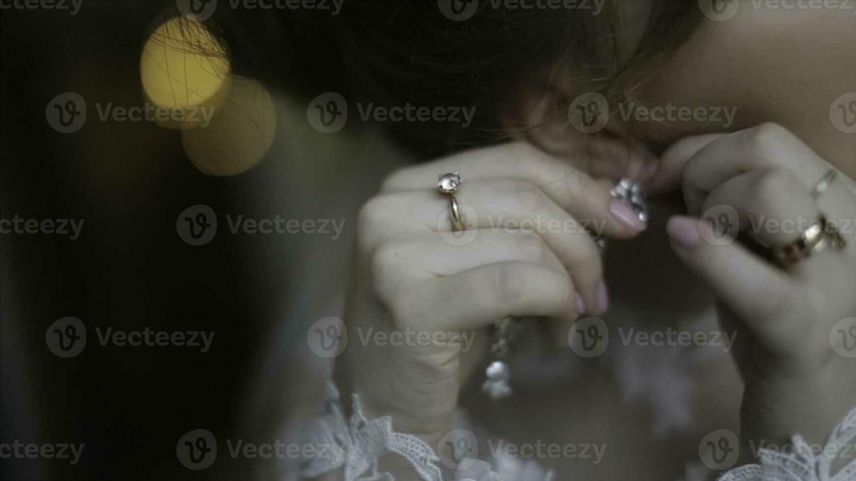 magnifique la mariée dans met sur boucle d'oreille. beauté modèle fille est portant bijoux pour mariage. mariage femelle portrait. femme avec frisé cheveux et dentelle voile. bijoux et beauté concept - proche en haut de portant photo