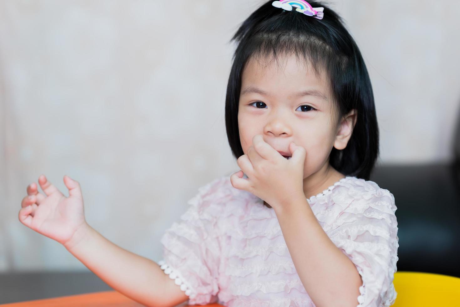 une jolie petite fille se gratte les lèvres à cause des démangeaisons. les enfants sourient secrètement. photo