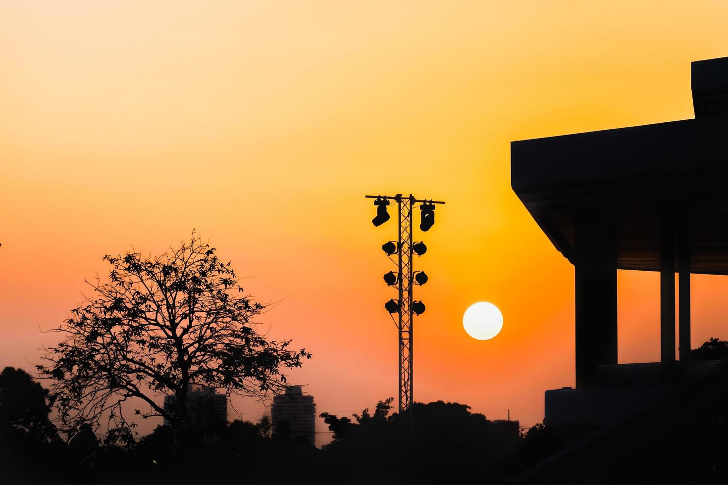 ciel orange et soleil du soir avec des silhouettes de bâtiments, de tours de transmission et d'arbres. photo