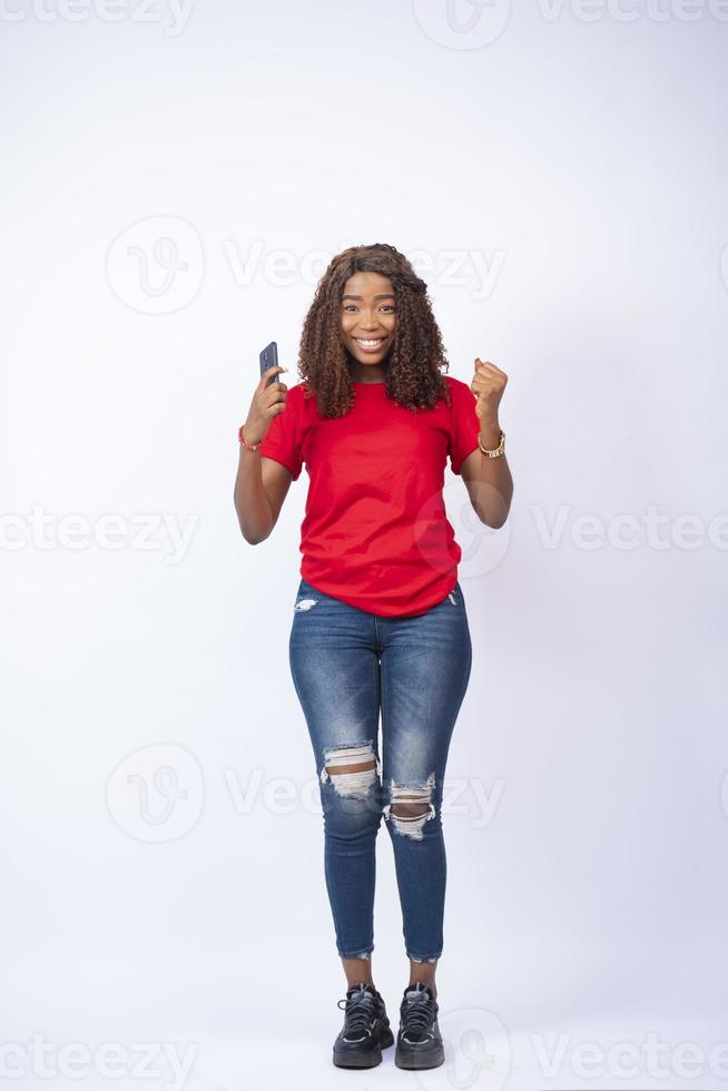 jeune femme noire heureuse et excitée tenant son téléphone photo