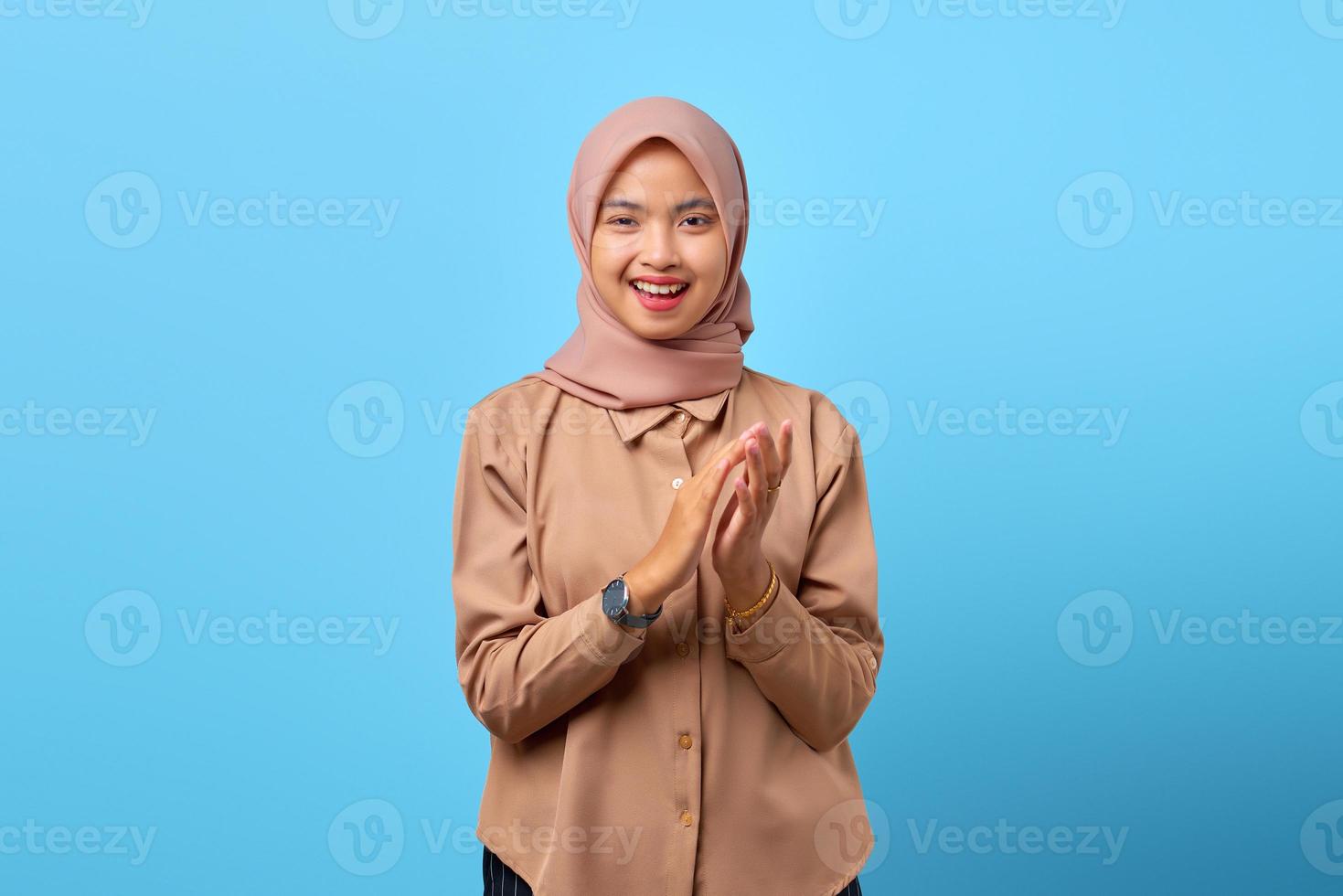 Portrait de joyeuse jeune femme asiatique gesticulant applaudissements félicitations sur fond bleu photo