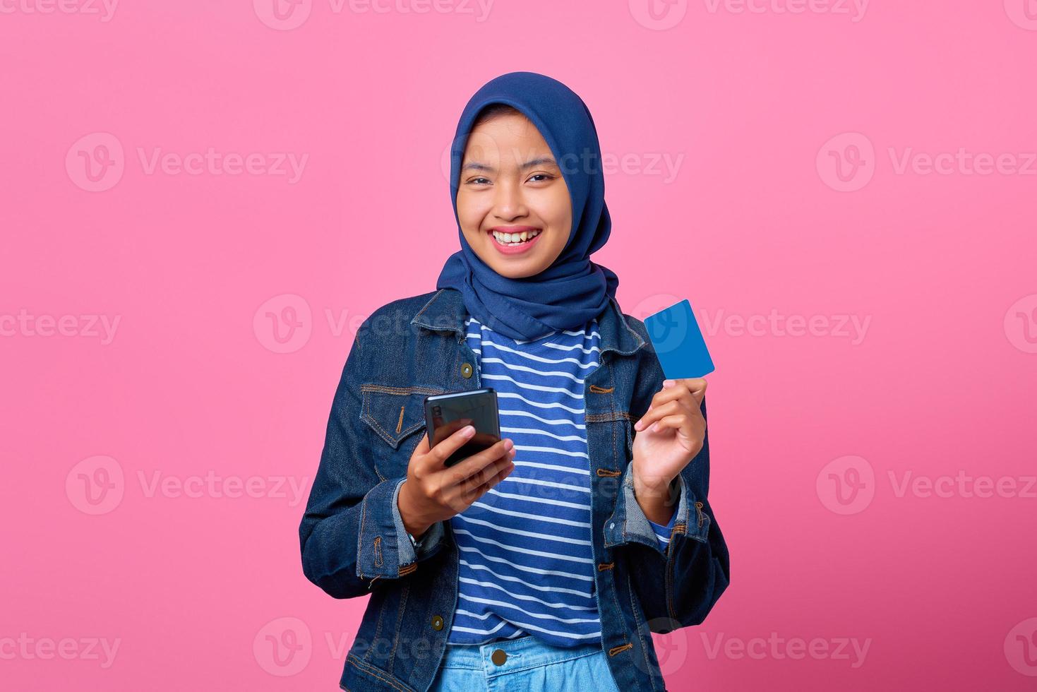 portrait d'une jeune femme asiatique souriante tenant un smartphone tout en montrant une carte de crédit photo