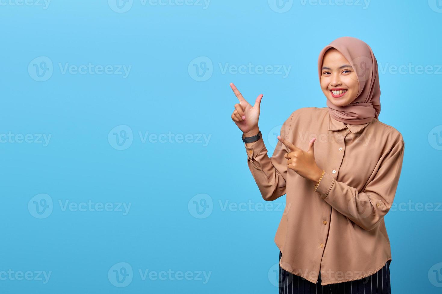 portrait de jeune femme asiatique souriante pointant vers l'espace de copie avec le doigt photo