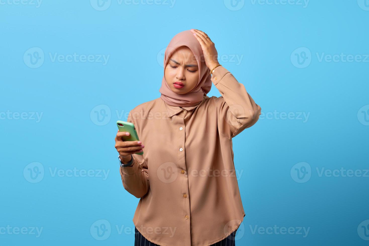 portrait de tristesse jeune femme asiatique tenant un téléphone portable avec la main sur la tête photo