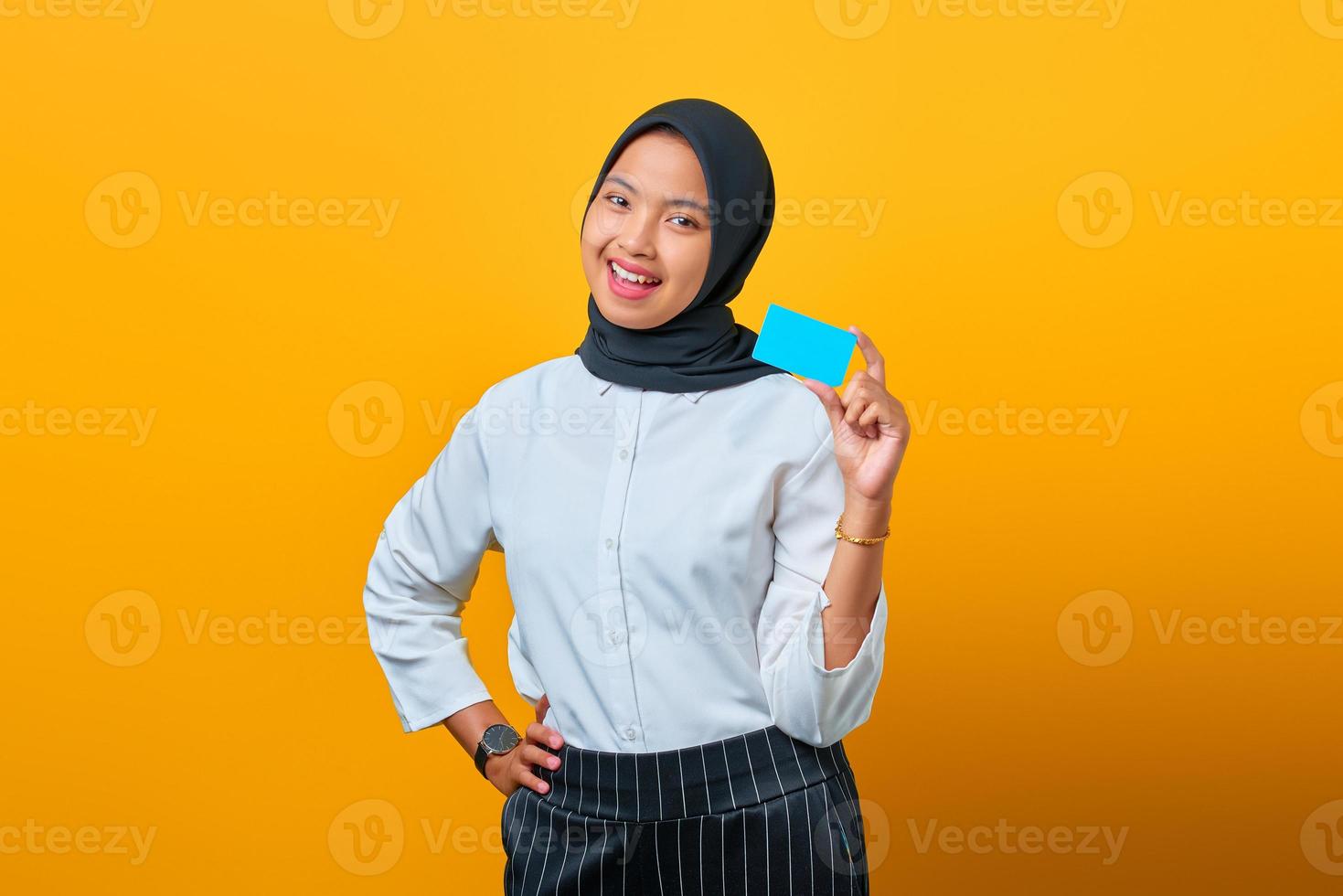 jolie jeune femme asiatique riant et tenant une carte de crédit sur fond jaune photo