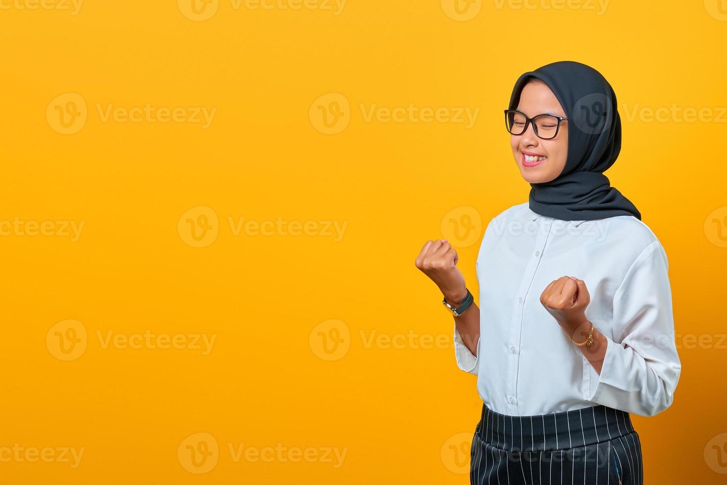 portrait d'une belle femme asiatique excitée célébrant le succès sur fond jaune photo