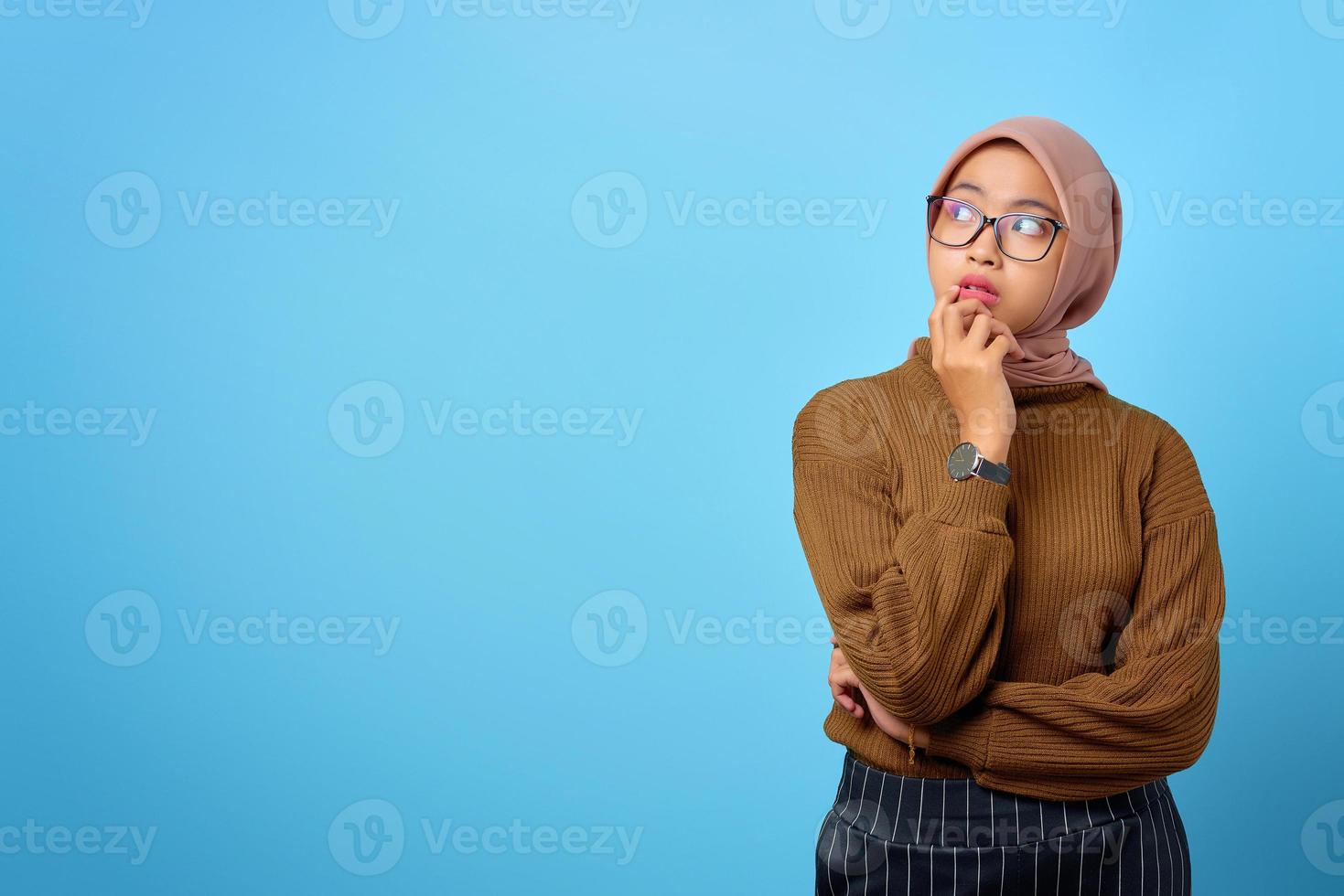 Une jeune femme asiatique pensive a l'air de réfléchir sérieusement à une question sur fond bleu photo