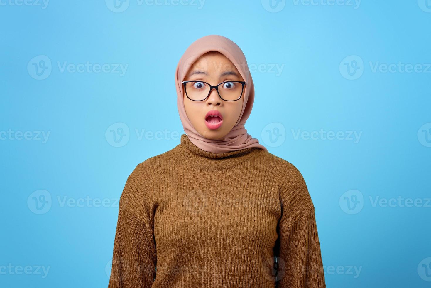 Portrait de jeune femme asiatique surprise avec la bouche ouverte sur fond bleu photo