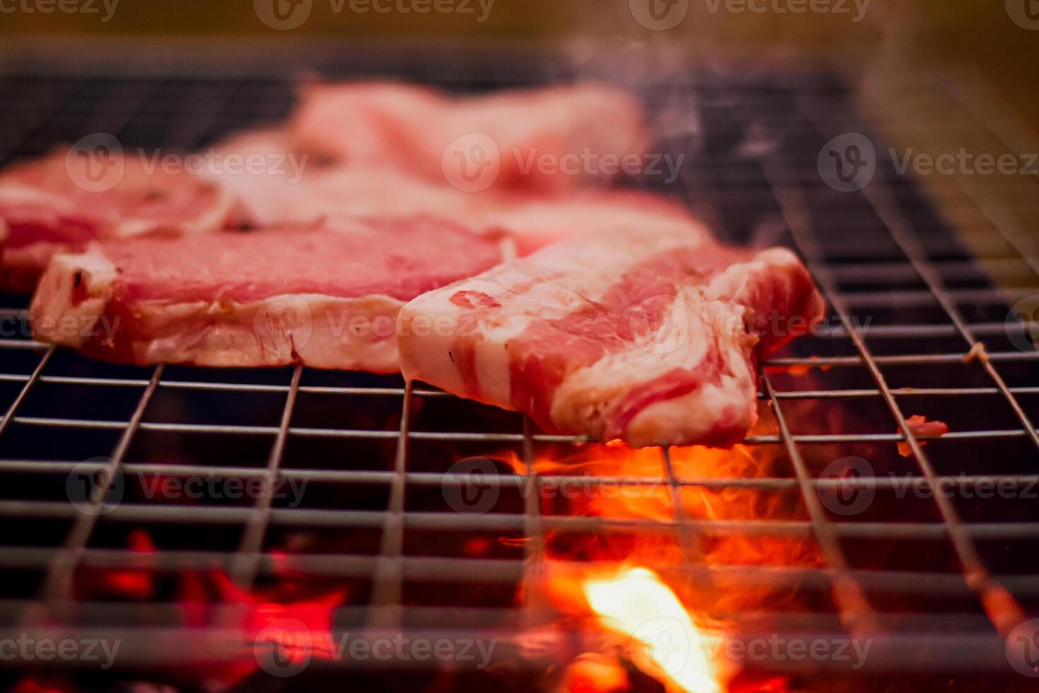 grillage porc sur inoxydable acier gril avec flammes sur noir arrière-plan, nourriture et cuisine concept. brûlant porc sur une charbon gril. photo