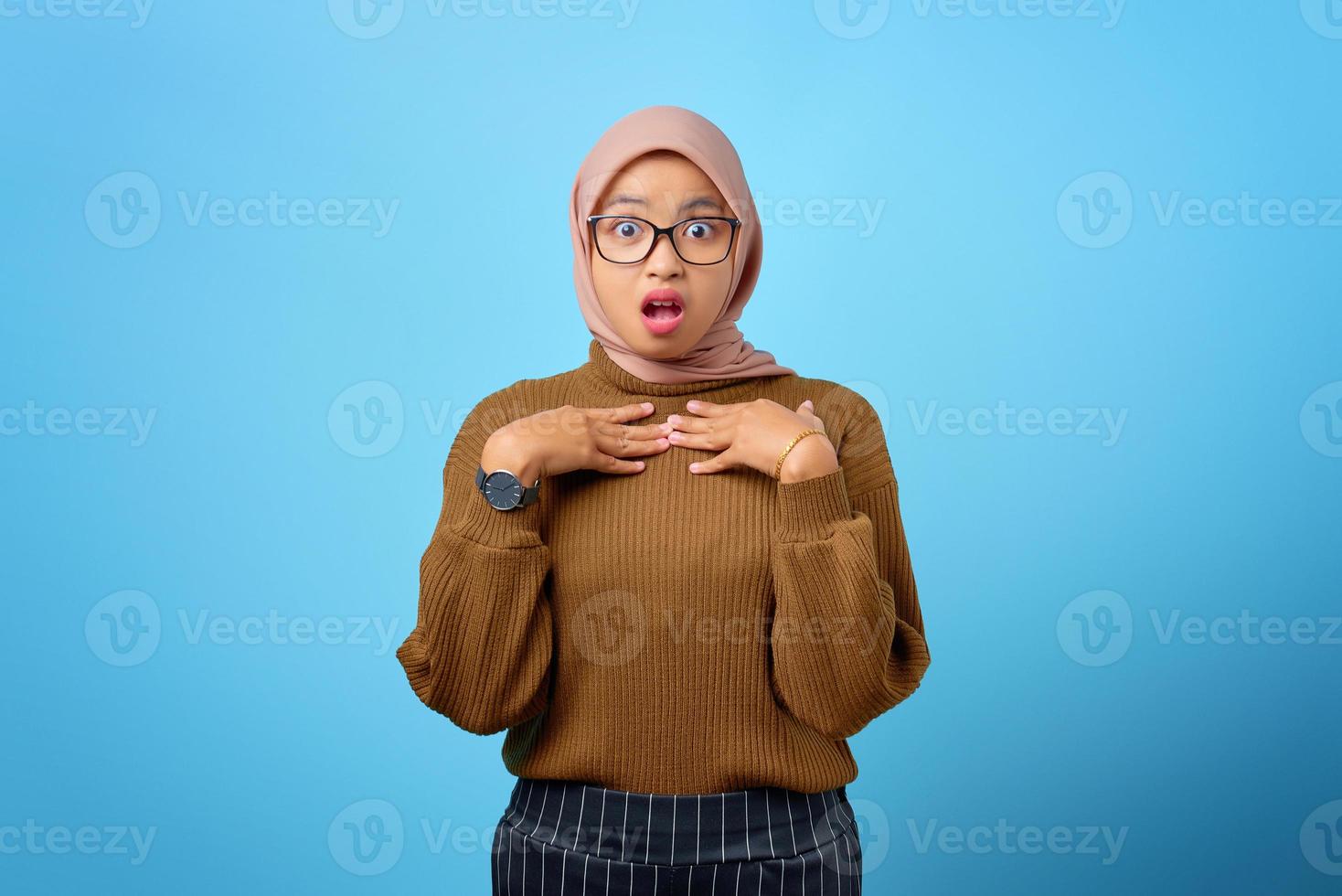 Portrait de jeune femme asiatique surprise avec la bouche ouverte sur fond bleu photo