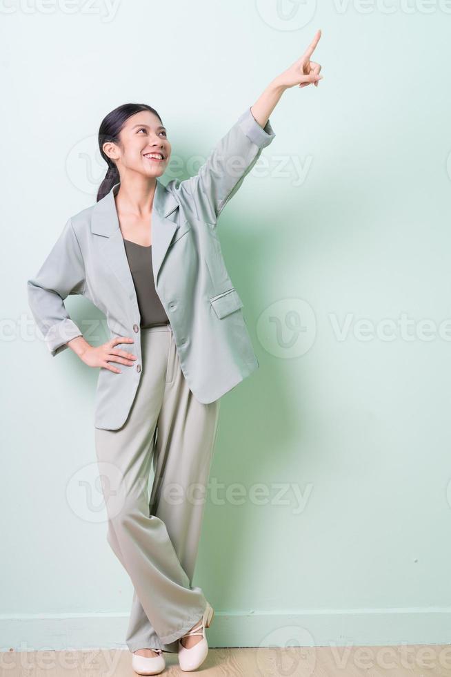 jeune femme d'affaires asiatique portant un costume vert sur fond vert photo