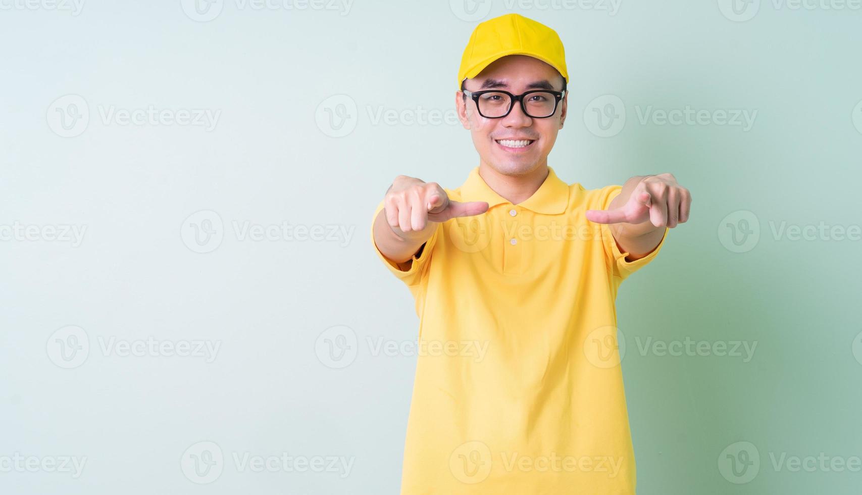 jeune livreur asiatique posant sur fond vert photo