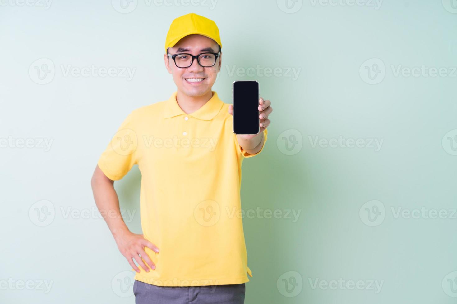 jeune livreur asiatique posant sur fond vert photo