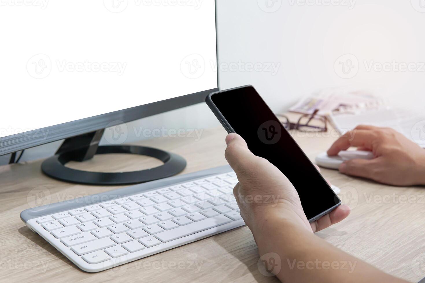 une homme utilisation intelligent téléphone chercher une nouvelles et Blog Les données sur le l'Internet avec bureau et nouvelles papier sur le bois table photo