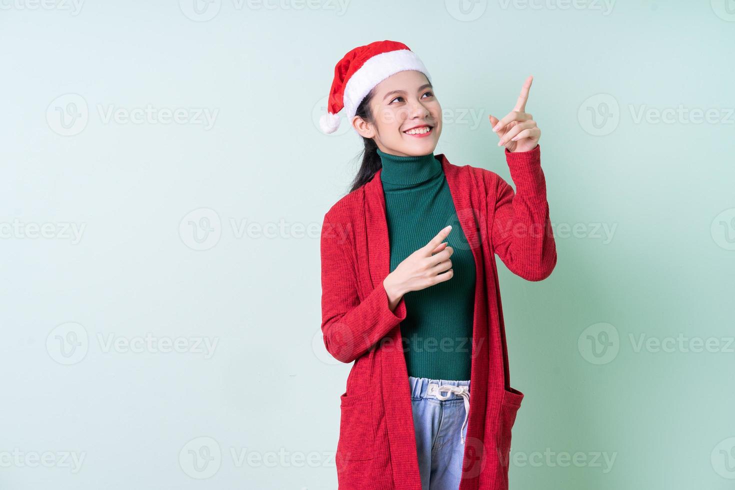 Jeune femme asiatique portant un chapeau de Noël sur fond vert, concept de Noël photo