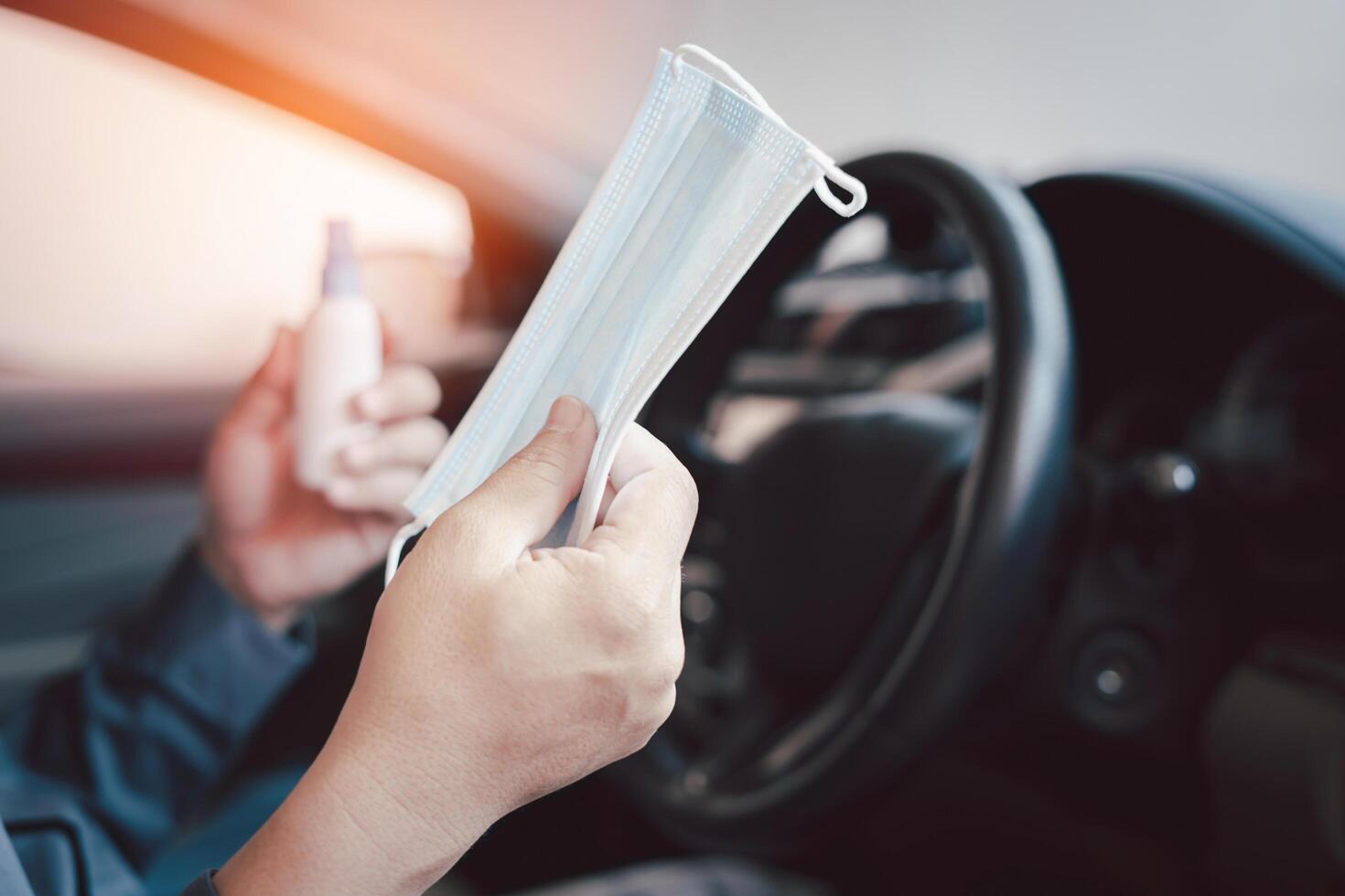 proche en haut main une homme tenir masque et de l'alcool vaporisateur pour prévenir germes et virus dans chaque journée et dans côté voiture dans Contexte photo