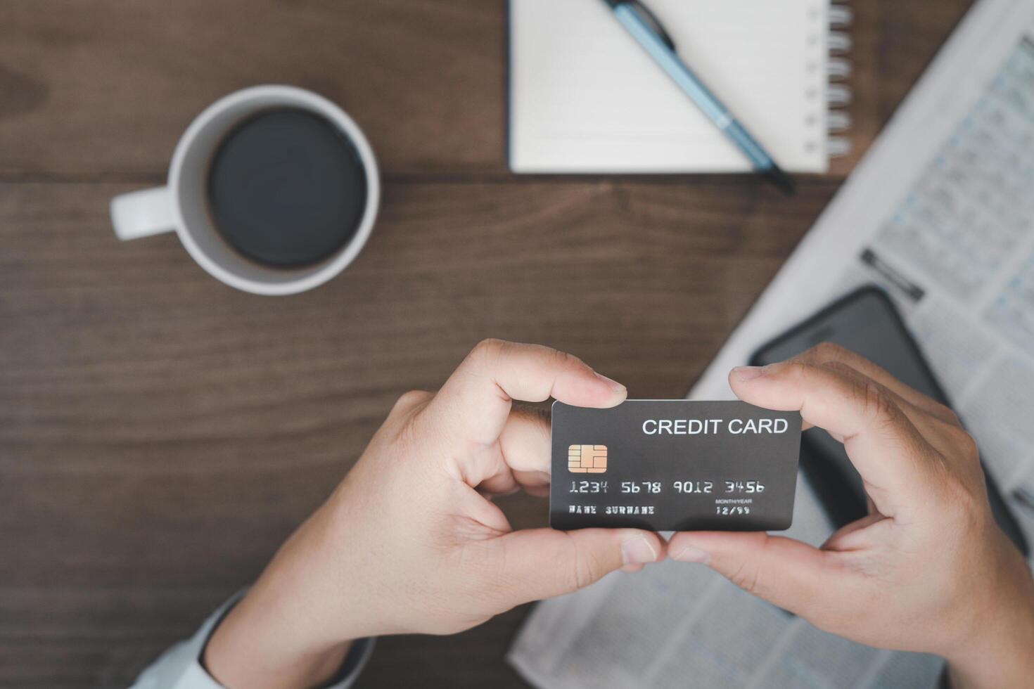 homme tenir crédit carte Payer pour nourriture et café avec téléphone intelligent carnet journal sur ancien bois table photo