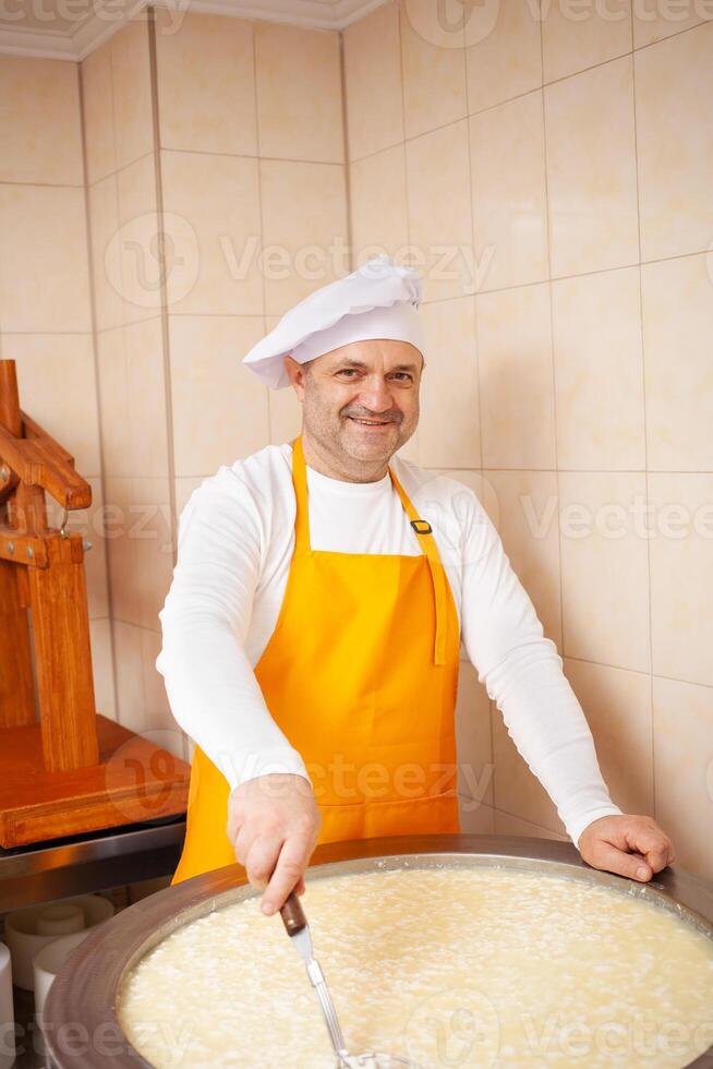 homme fait du fromage, bout Lait dans citerne, chauffage, température. Lait pliant processus, Accueil production, entreprise, individuel entrepreneur photo