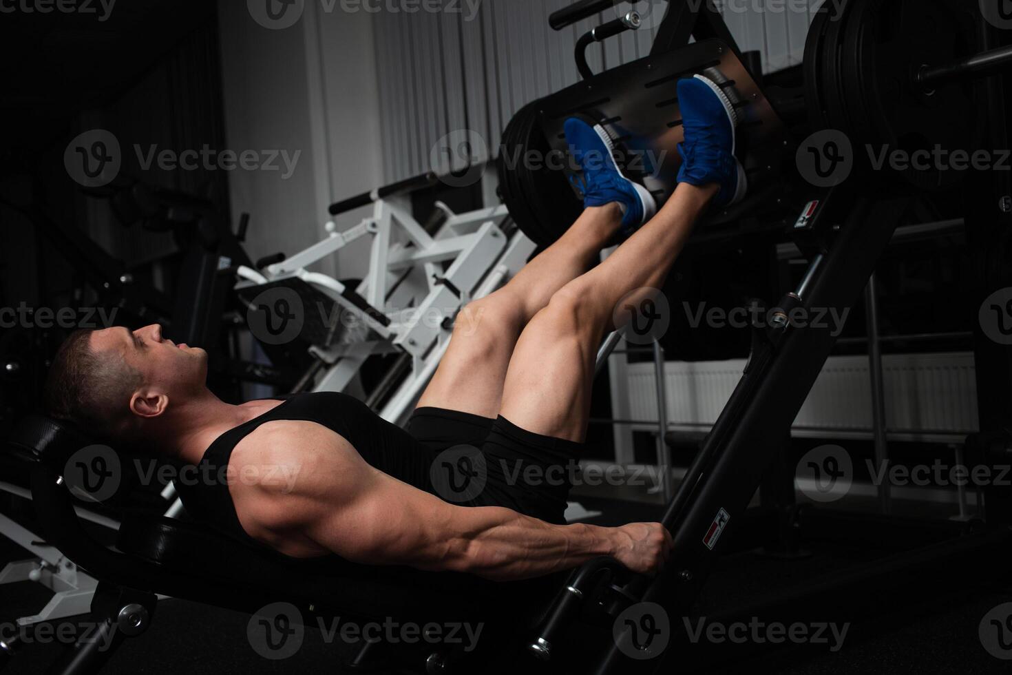 portrait de une Beau Masculin entraîneur dans salle de sport. le athlète Est-ce que un exercice sur le simulateur dans le salle de sport. construit muscle, pièces des sports, une en bonne santé mode de vie. photo