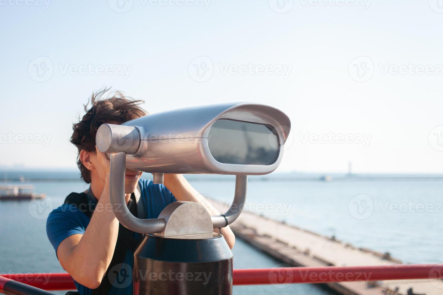 homme regards par Stationnaire jumelles. binoscope sur observation plate-forme près mer. port de mer dans Odessa. coûteux yachts sur le jetée. commercial machine, vente entreprise. touristique voyages photo