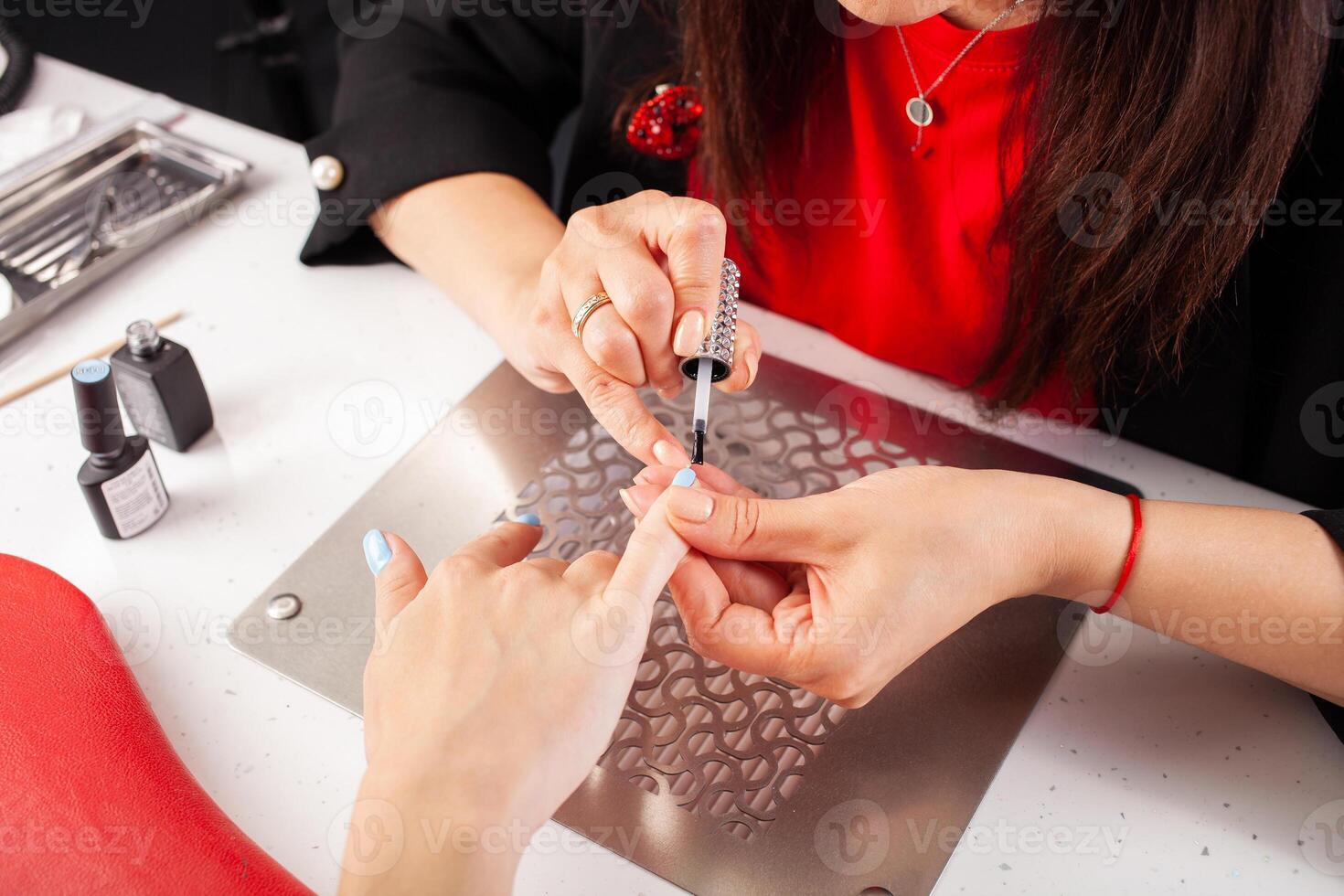 le manucure détient mains de le client dans beauté salon sur bureau pour manucure avec clou polit, serviettes, crèmes et éclairage instruments photo