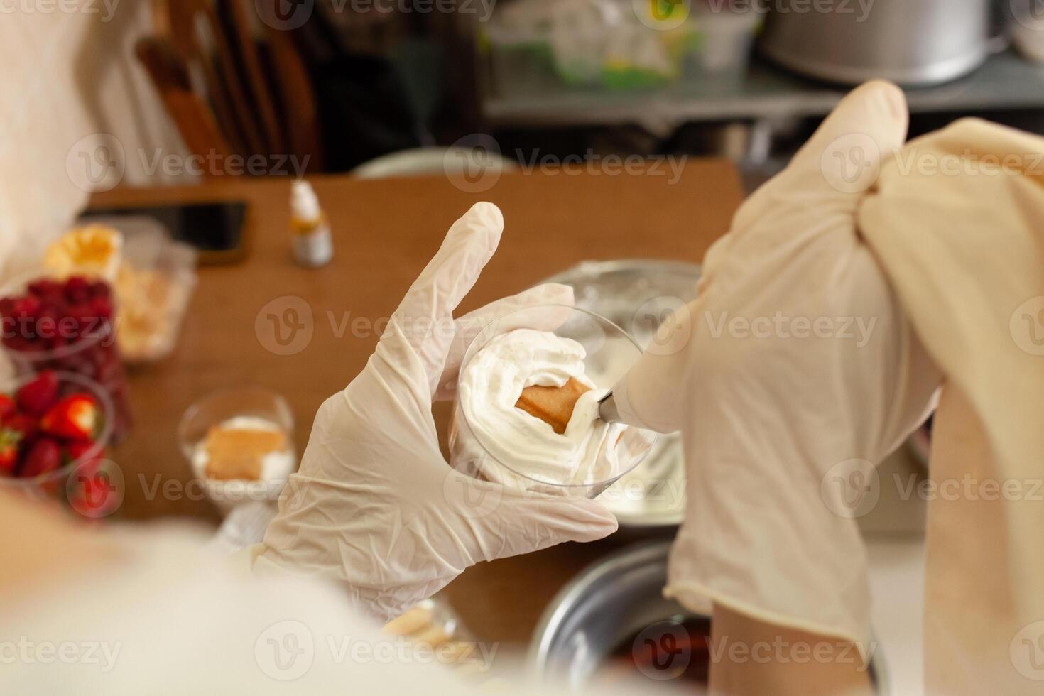 le Pâtisserie chef décore le tiramisu dans une verre avec fouetté crème. photo