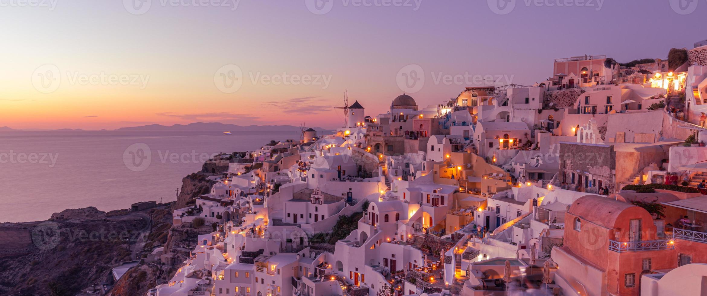 magnifique île au coucher du soleil de santorin en grèce, beau village blanchi à la chaux oia avec moulin à vent de l'église pendant le coucher du soleil, lumières de la rue, vacances d'été romantiques, célèbre destination de voyage pour un couple de lune de miel photo