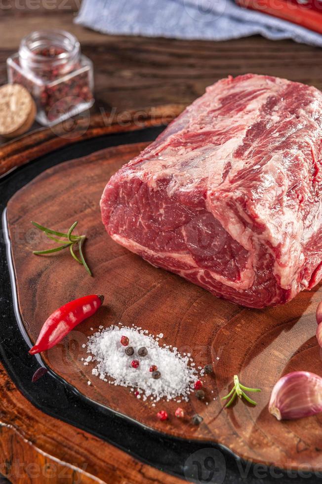 entrecôte de boeuf crue sur une planche à découper en bois avec des épices. photo