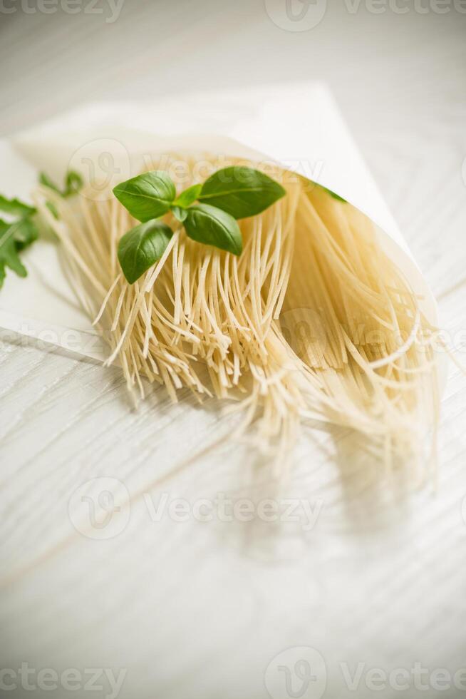 fait maison mince séché Oeuf nouilles dans papier sac avec basilic photo