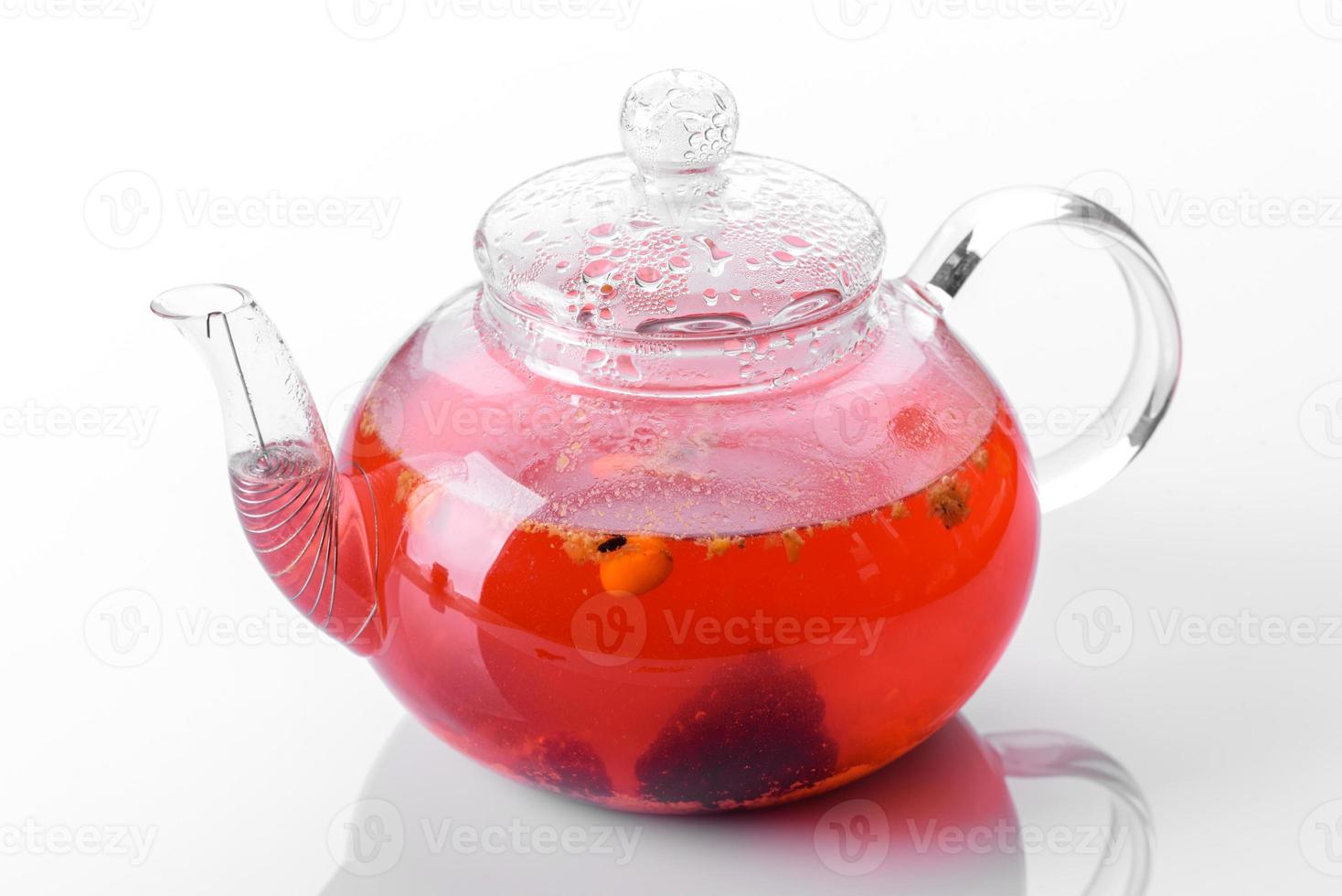 délicieux thé de baies et de fruits dans une belle théière en verre sur fond blanc avec reflet photo
