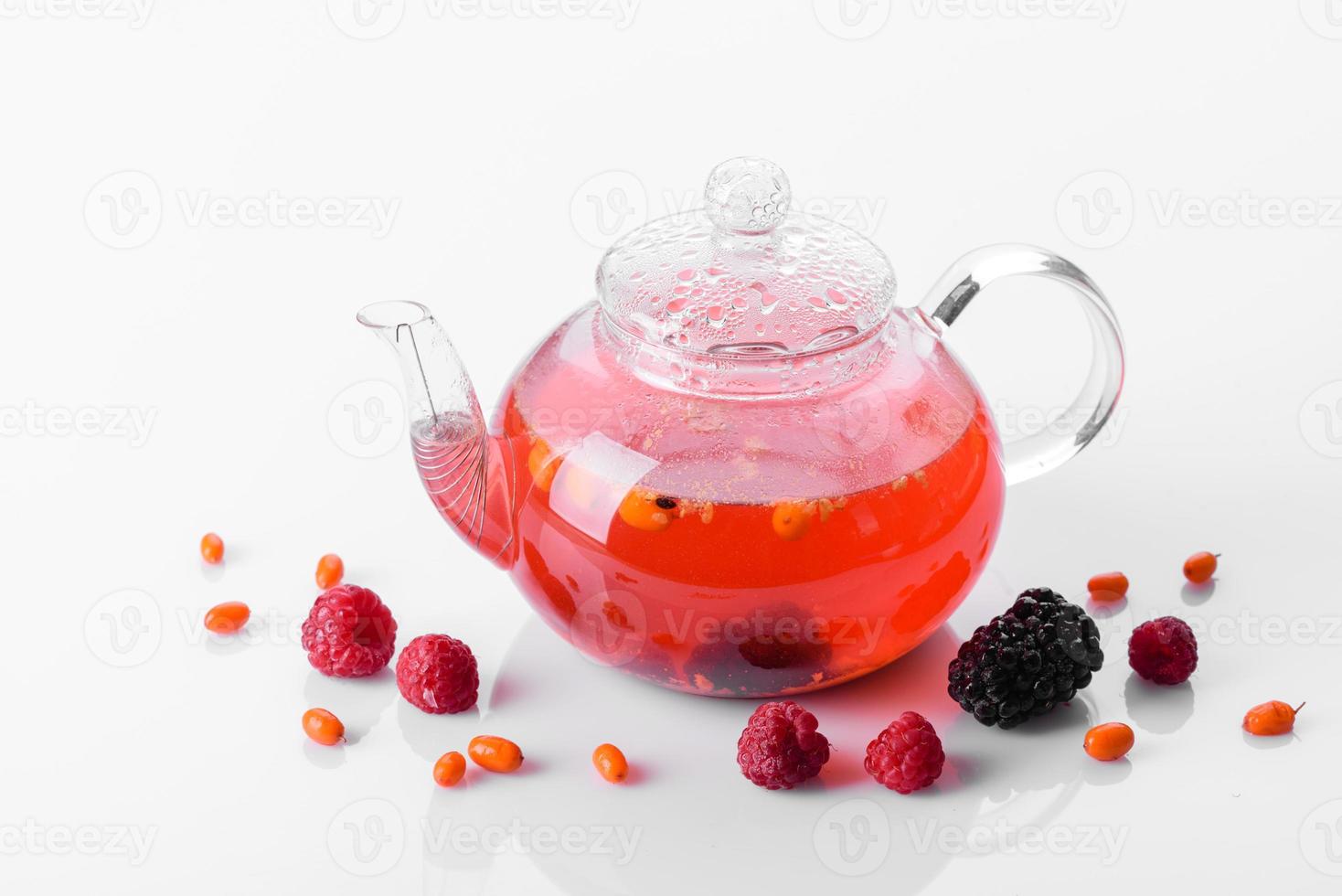 délicieux thé de baies et de fruits dans une belle théière en verre sur fond blanc avec reflet photo