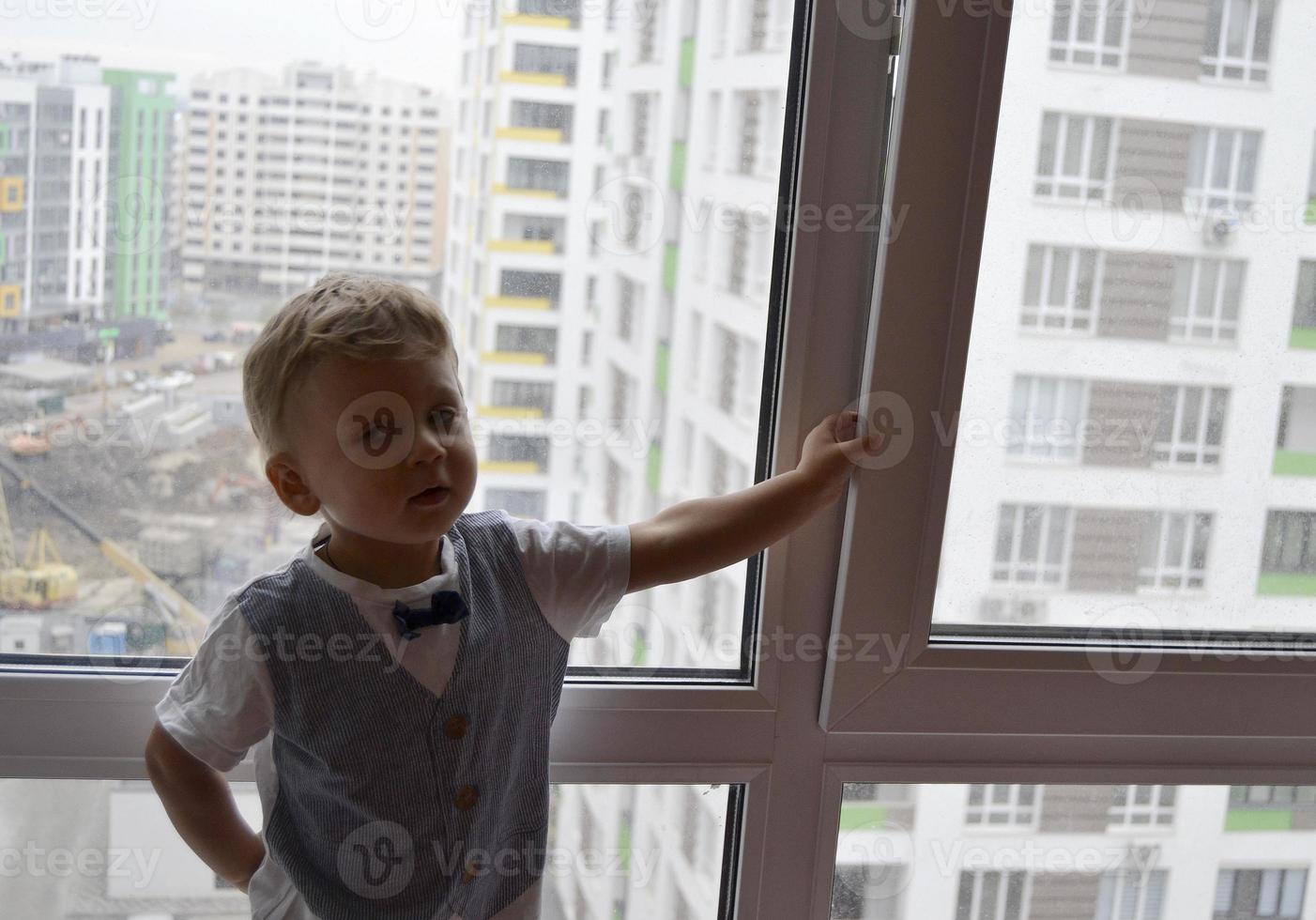 beau petit garçon avec un visage d'enfant posant un photographe près de la fenêtre photo