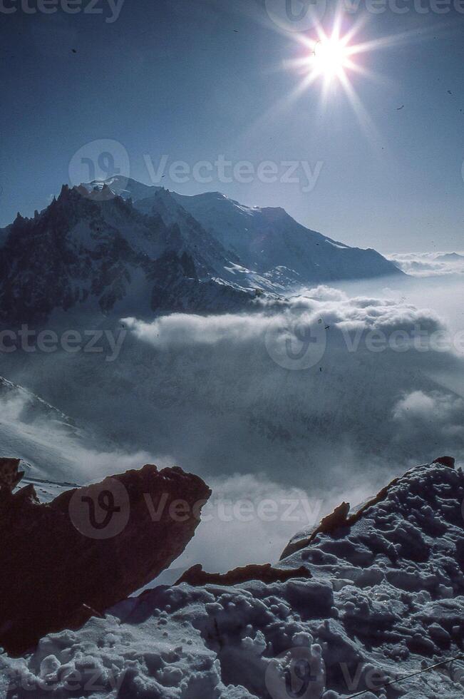 une la personne permanent sur une Montagne Haut avec une neige couvert paysage photo