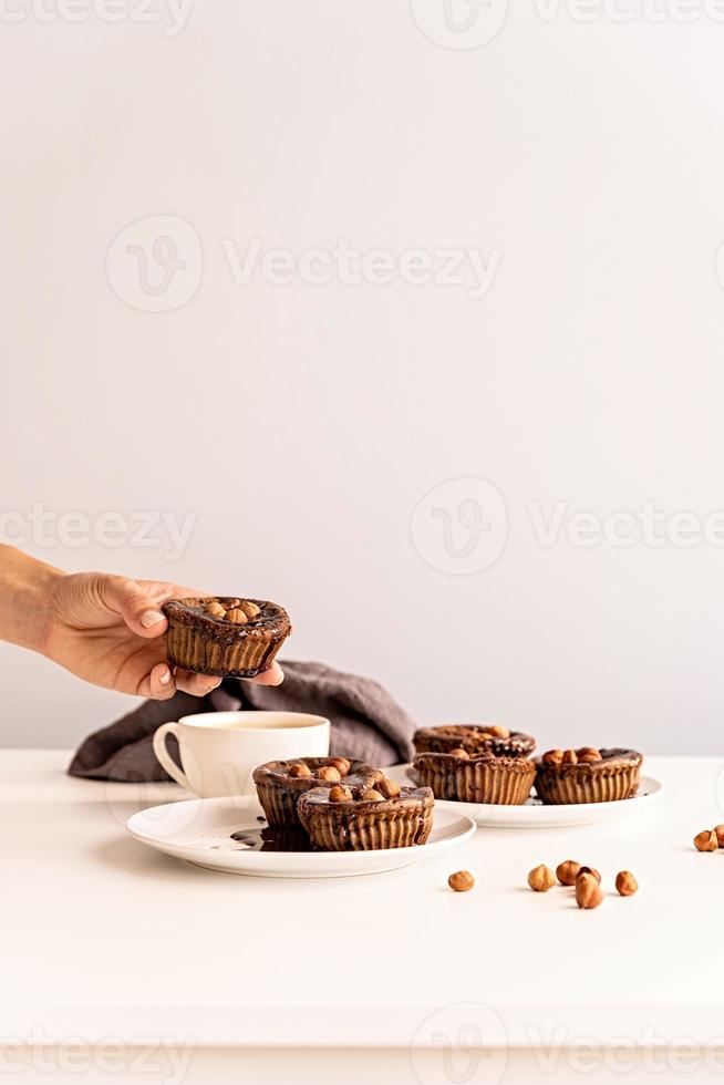 cupcakes au chocolat faits maison avec glaçage, noix et une tasse de café sur la vue de face de la table blanche photo