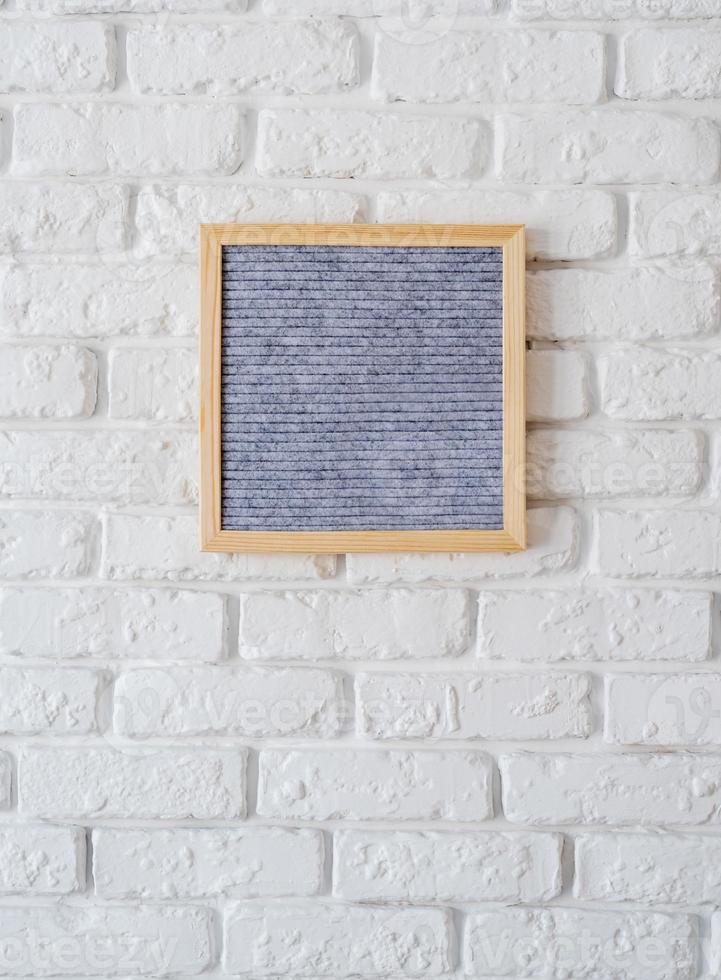 Tableau à lettres en feutre gris accroché au mur de briques blanches photo